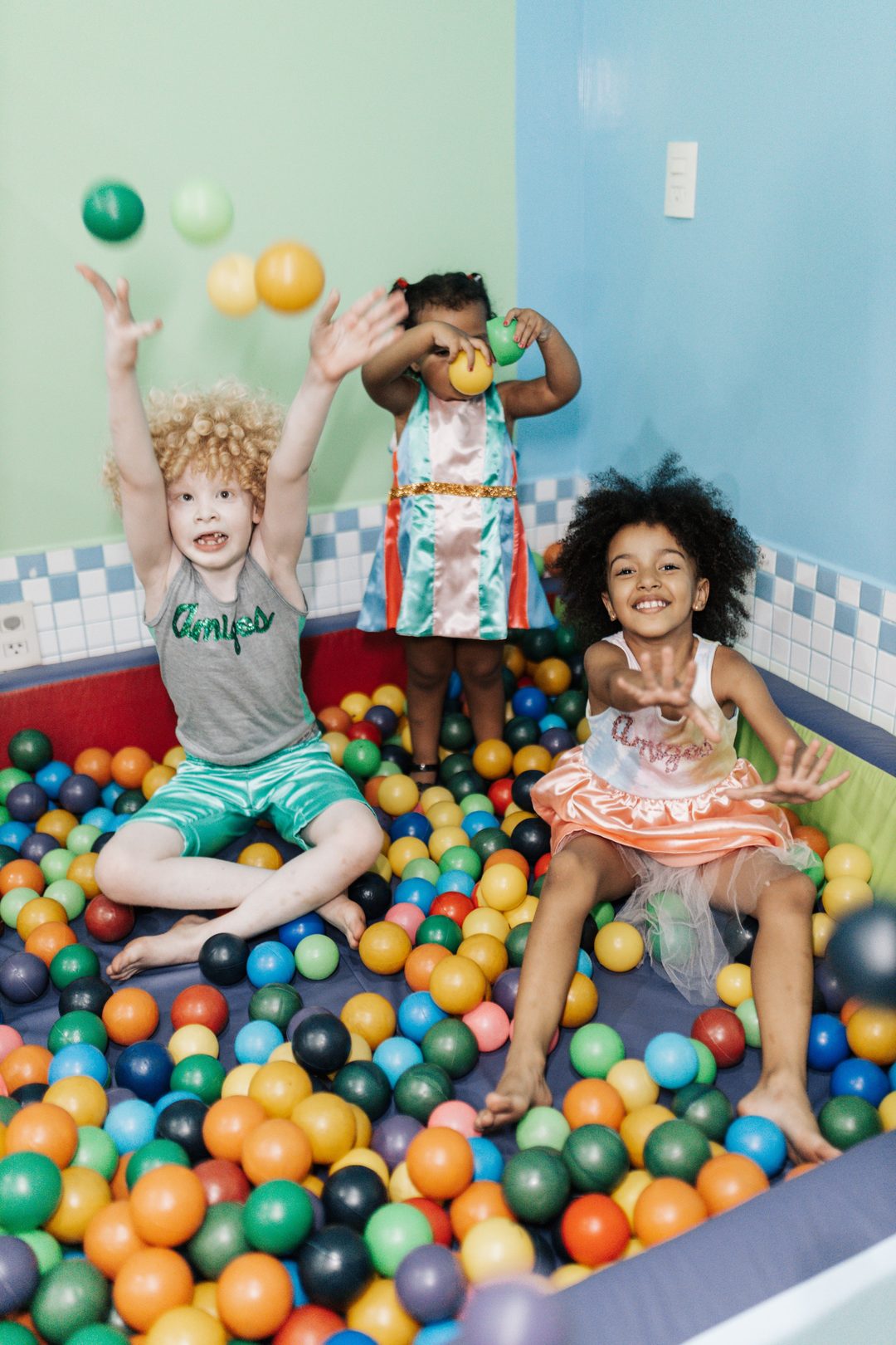 Young children smiling and playing in a colourful ball pit